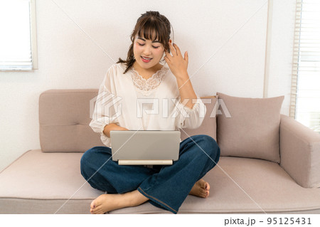 自宅でノートパソコンを操作する若い女性 自宅でノートパソコンを操作する若い女性 95125431