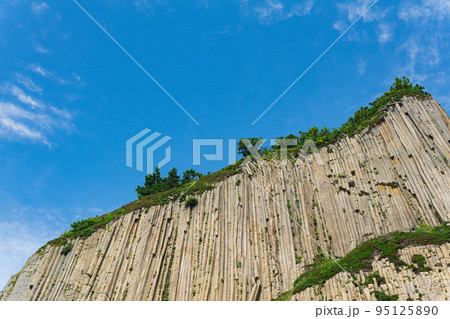 top of columnar volcanic basalt cliff against the background of the sky with clouds top of columnar volcanic basalt cliff against the background of the sky with clouds 95125890