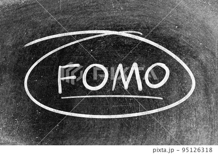 White chalk hand writing in word FOMO (abbreviation of fear of missing out) and circle shape on blackboard background 95126318