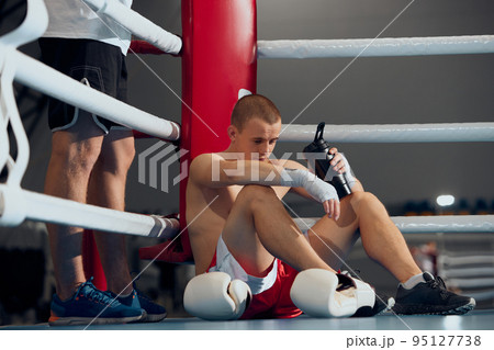 Pre-fight consultation. Young boxer training with personal coach, trainer at boxing ring at sports gym. Sport, strategy, studying, skills and achievements 95127738