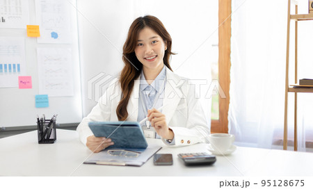 Businesswoman using laptop to work, Asian woman working in the office, Financial clerk or accountant with documents and equipment working on the desk, Using tablet for financial transactions. Businesswoman using laptop to work, Asian woman working in the office, Financial clerk or accountant with documents and equipment working on the desk, Using tablet for financial transactions. 95128675