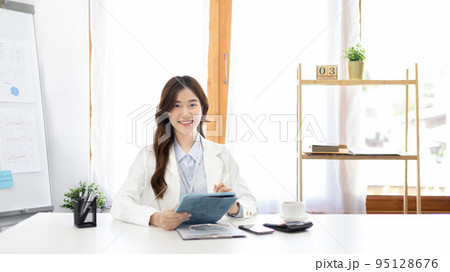 Businesswoman using laptop to work, Asian woman working in the office, Financial clerk or accountant with documents and equipment working on the desk, Using tablet for financial transactions. Businesswoman using laptop to work, Asian woman working in the office, Financial clerk or accountant with documents and equipment working on the desk, Using tablet for financial transactions. 95128676
