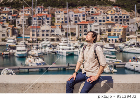 Man tourist enjoying the views of Architecture and luxury yachts in Lustica Bay, Montenegro. Travel around Montenegro concept. Go Everywhere 95129432