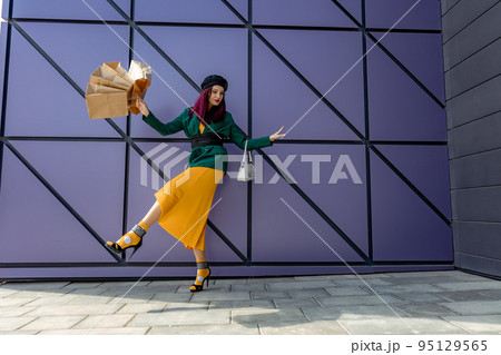 A happy shopaholic girl throws her bags near a shopping center. Have fun shopping on Black Friday. the girl in the store is happy with her purchases, throws packages. Consumer concept. A happy shopaholic girl throws her bags near a shopping center. Have fun shopping on Black Friday. the girl in the store is happy with her purchases, throws packages. Consumer concept. 95129565