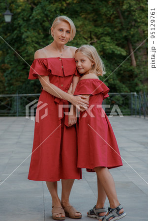 Close up portrait of mother and daughter hugging. Portrait of cheerful mother and daughter. They are wearing red clothes. Happy family blonde mother and daughter. Close up portrait of mother and daughter hugging. Portrait of cheerful mother and daughter. They are wearing red clothes. Happy family blonde mother and daughter. 95129761