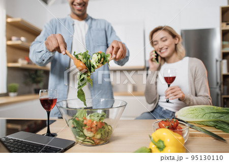 Focus on man's hands holding wooden spoons and mixing ingredients in glass bowl Focus on man's hands holding wooden spoons and mixing ingredients in glass bowl 95130110