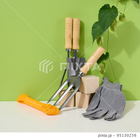 Garden tools for processing beds in the garden and textile gloves on a green background 95130256