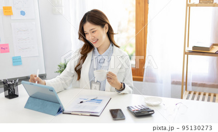 Businesswoman using laptop to work, Asian woman working in the office, Financial clerk or accountant with documents and equipment working on the desk, Using tablet for financial transactions. Businesswoman using laptop to work, Asian woman working in the office, Financial clerk or accountant with documents and equipment working on the desk, Using tablet for financial transactions. 95130273