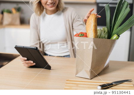 Cropped view of happy woman cooking healthy food looking on paper bag with vegetables 95130441