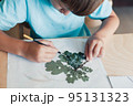 8 years old child siting by desk and doing herbarium on album sheet 95131323