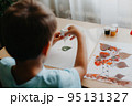 Cute child sitting at desk and making picture from dry birch leaves 95131327