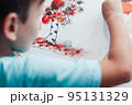 Cute child sitting at desk and making picture from dry birch leaves 95131329