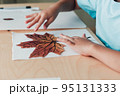 8 years old child siting by desk and doing herbarium on album sheet 95131333