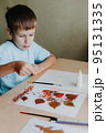 Cute child sitting at desk and making picture from dry birch leaves 95131335