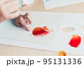 Cute child sitting at desk and making picture from dry birch leaves 95131336