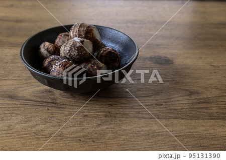 木材背景の黒い食器に盛ったキヌカツギ 95131390