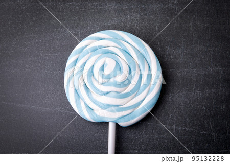 Blue candy on a stick, lollipop. Dark chalkboard background Blue candy on a stick, lollipop. Dark chalkboard background 95132228