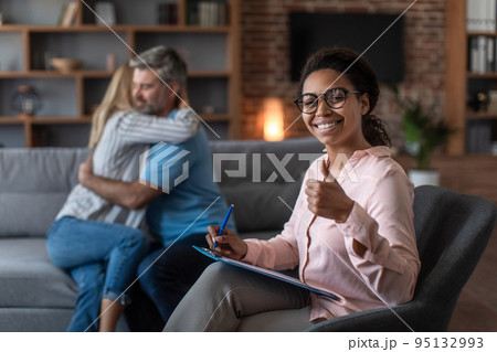 Smiling black young doctor in glasses show thumb up approves therapy of mature european couple 95132993
