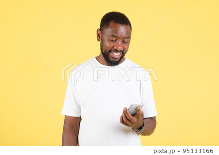 Black Man Using Phone Standing Over Yellow Background In Studio Black Man Using Phone Standing Over Yellow Background In Studio 95133166