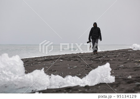 Photographer picking up pieces of icebergs Photographer picking up pieces of icebergs 95134129
