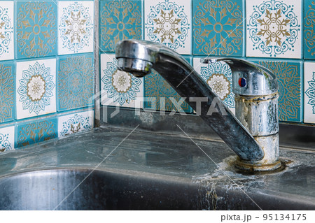 Old rusty sink faucet in kitchen. Rust streaks, calcium scale, hard water. Old rusty sink faucet in kitchen. Rust streaks, calcium scale, hard water. 95134175
