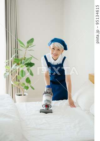 ベッドを掃除するハウスキーパーのシニア女性 95134615