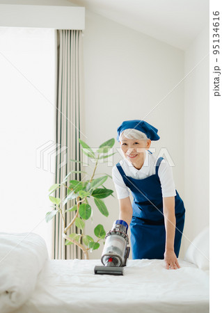 ベッドを掃除するハウスキーパーのシニア女性 95134616