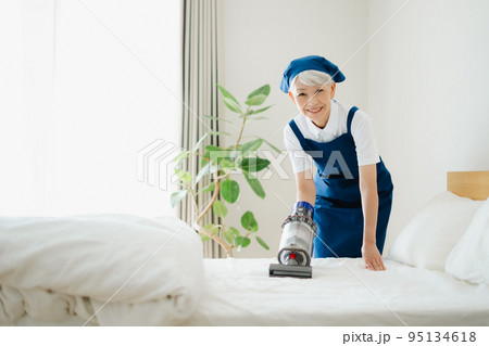 ベッドを掃除するハウスキーパーのシニア女性 95134618