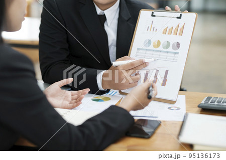 Businessmen working, discussing, analyzing using laptop and graphs. 95136173