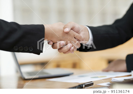 Two businessmen shaking hands agreeing on the deal. Two businessmen shaking hands agreeing on the deal. 95136174