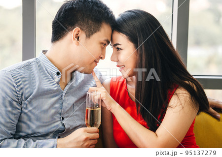 Smile asian lover couple male hand hold a champagne. She touch finger on man face. 95137279