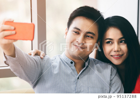 Romantic asian couple take a selfie relax in living room together. Romantic asian couple take a selfie relax in living room together. 95137288