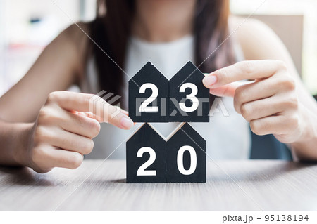 Businesswoman hands holding key and 2023 Happy New Year with house model on table office. New House, Financial, Property insurance, real estate, savings and New Year Resolution concepts 95138194