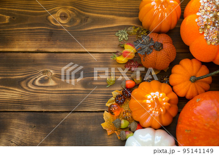 Orange and white pumpkins and jack lantern with his eyes and mouth cut out on a wooden table with yellow autumn maple leaves, berries. Autumn mood, halloween, home decor Orange and white pumpkins and jack lantern with his eyes and mouth cut out on a wooden table with yellow autumn maple leaves, berries. Autumn mood, halloween, home decor 95141149