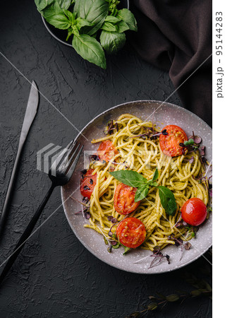 Vegetarian pasta spaghetti with basil pesto and cherry tomatoes 95144283