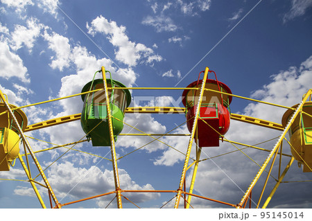 Attraction (carousel) ferris wheel on the background of the cloudy sky Attraction (carousel) ferris wheel on the background of the cloudy sky 95145014