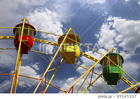 Attraction (carousel) ferris wheel on the background of the cloudy sky Attraction (carousel) ferris wheel on the background of the cloudy sky 95145137