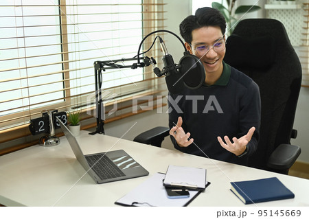 Man podcaster using laptop and microphone to recording podcast from home studio. Radio, podcasts and technology concept 95145669