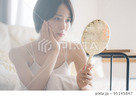 肌荒れに悩む手鏡を持つ女性 95145847