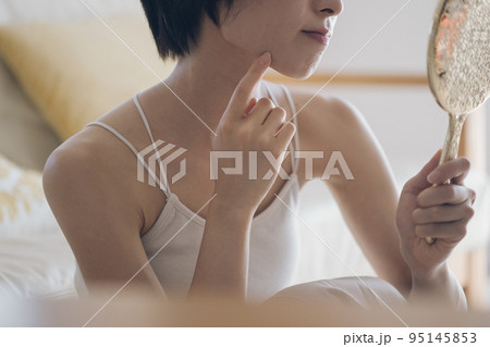 肌荒れに悩む手鏡を持つ女性 95145853