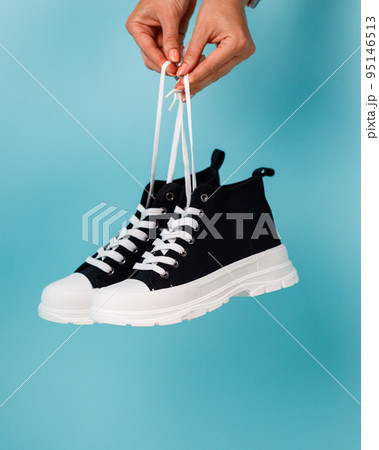 Stylish and fashionable model of black and white sneakers on blue background. 95146513