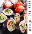 Large sushi set of various sushi rolls is served on black square metal slate. 95146566