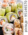 Large sushi set of various sushi rolls is served on black square metal slate. 95146570