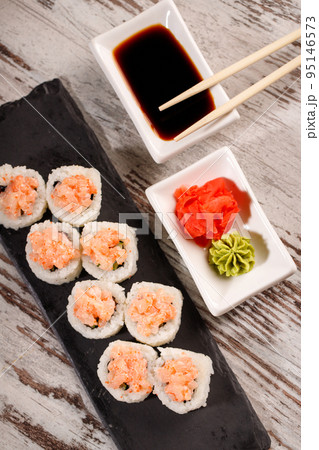 Sushi roll covered with chopped salmon and caviar is served on rectangular black slate. Sushi roll covered with chopped salmon and caviar is served on rectangular black slate. 95146573
