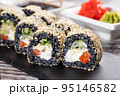 Close up of original unconventional sushi with black rice and covered with white sesame seeds. 95146582
