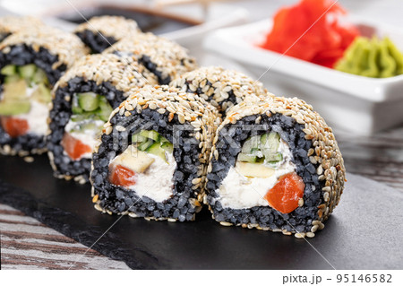 Close up of original unconventional sushi with black rice and covered with white sesame seeds. 95146582