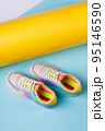 Pair of fashionable bright sports shoes for teens standing on orange-blue background. 95146590