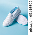 Promotional photo of pair of white women's moccasins on light blue background. 95146609