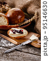 Sliced piece of freshly baked buns with butter and jam on wooden kitchen board. 95146630