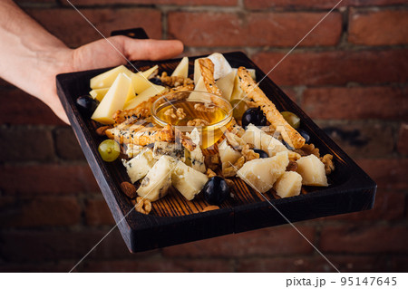 Cheese plate with honey, grapes and nuts 95147645